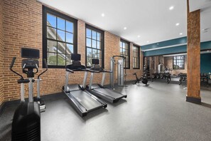 A gym with treadmills, weight machines, and a wall of dumbbells.