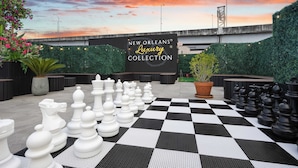 Ett schackbräde placerat på ett rutigt golv, med en skylt i bakgrunden som lyder: ”New Orleans Luxury Collection”.