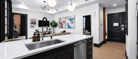 Una cocina moderna con una isla grande, muebles negros y luminarias colgantes.