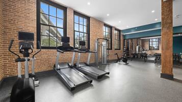 A gym with treadmills, weight machines, and a wall of dumbbells.