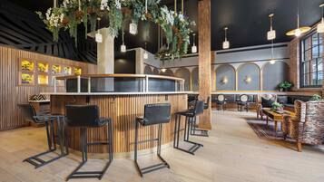 Una zona de bar con taburetes de madera, plantas colgantes e iluminación colgante.