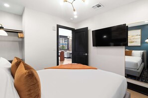 A hotel room with a bed, a television, a door leading to a balcony, and a window. - Connecting 6 Bedroom W/ 2 Living Rooms Sleeps 16 (New Orleans)