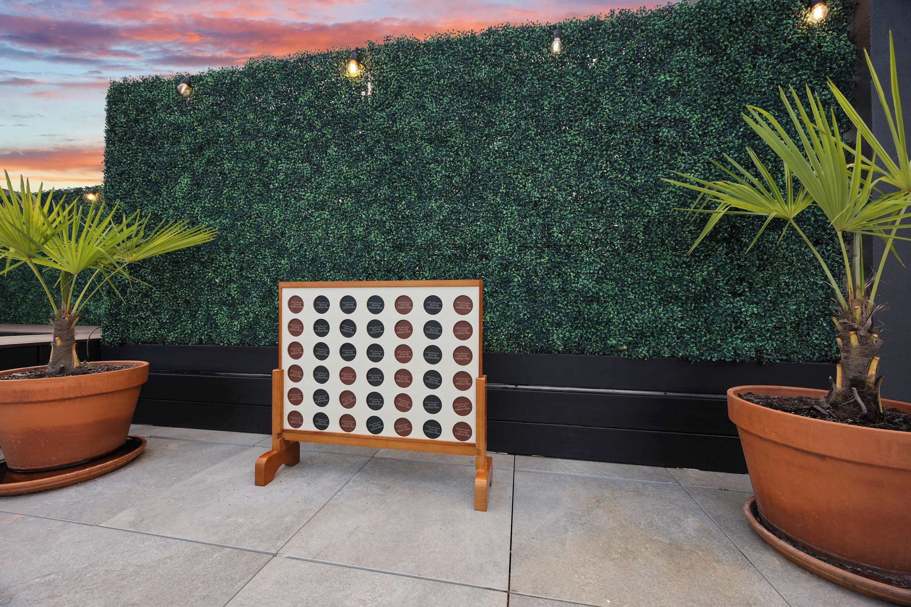 A display board with multiple circular labels, potted plants, and a hedge wall.