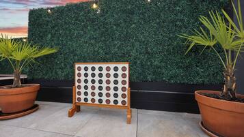 A display board with multiple circular labels, potted plants, and a hedge wall.