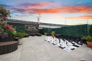 An outdoor area with a chessboard, seating, and a sign for 'New Orleans Luxury Collection'. - Downtown Hotel 2 King Bed Suite | Gym | Rooftop (New Orleans)