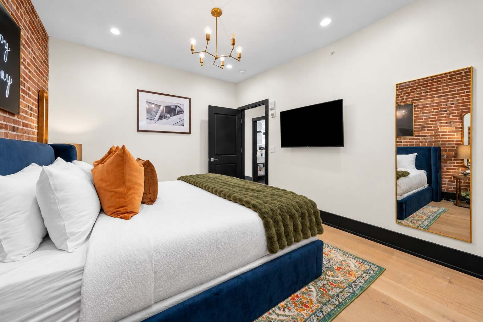 A modern bedroom with a bed, pillows, a television, and a mirror.