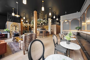 A modern interior with seating areas, a bar, and a reception desk. - Downtown Hotel 2 King Bed Suite | Gym | Rooftop (New Orleans)
