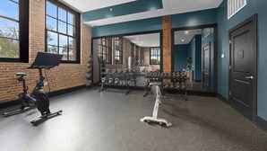 A gym with exercise equipment, large windows, and a brick wall. - Bachelorette Suite Perfect for a Memorable Stay (New Orleans)