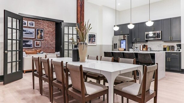 A modern kitchen with dark cabinets, a white island, and pendant lighting. - Bachelorette Suite Perfect for a Memorable Stay (New Orleans)