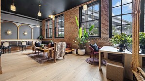 A spacious room with a brick wall, large windows, and a mix of seating including a sofa and chairs. - Bachelorette Suite Perfect for a Memorable Stay (New Orleans)