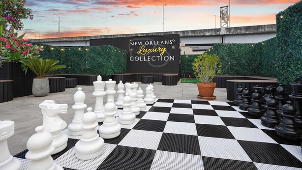A chessboard set up on a checkered floor with a sign reading 'New Orleans Luxury Collection' in the background. - All New | King bed | Gym | Rooftop (New Orleans)