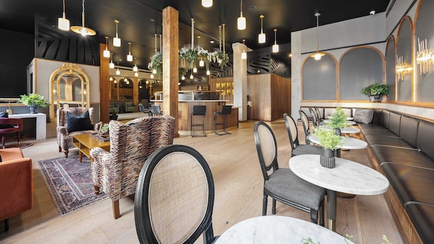 A modern interior with seating areas, a bar, and a reception desk. - Boutique Suite | Rooftop | Convention Ctr (New Orleans)