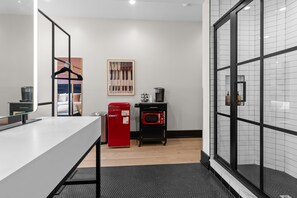 Ein modernes Hotelzimmer mit einer Küchenzeile, einem großen Spiegel, einem Bett mit Kopfteil und Blick durch eine Glastür.
