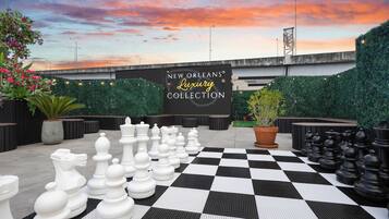 A chessboard set up on a checkered floor with a sign reading 'New Orleans Luxury Collection' in the background.