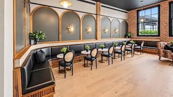 A restaurant with a long counter, black leather seating, and a brick wall.