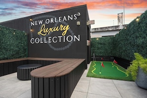 A wall with 'NEW ORLEANS Luxury Collection' signage, a wooden bench, and a miniature golf setup. - Sleeps 10 | Luxury 4BR Downtown Hotel (New Orleans)