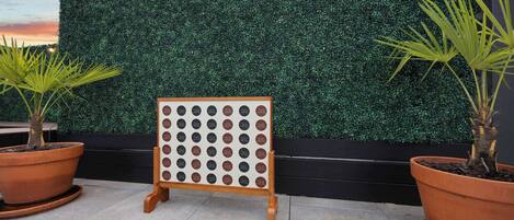 A display board with multiple circular labels, potted plants, and a hedge wall.