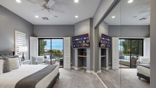 A modern bedroom with a large bed, a ceiling fan, and a TV mounted on the wall. - The Estate | Lake Views w/Heated Pool, Spa, & Boat (Glendale)