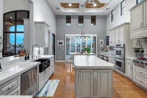 A spacious kitchen with a central island, stainless steel appliances, and a view to the outside. - The Estate | Lake Views w/Heated Pool, Spa, & Dock (Glendale)