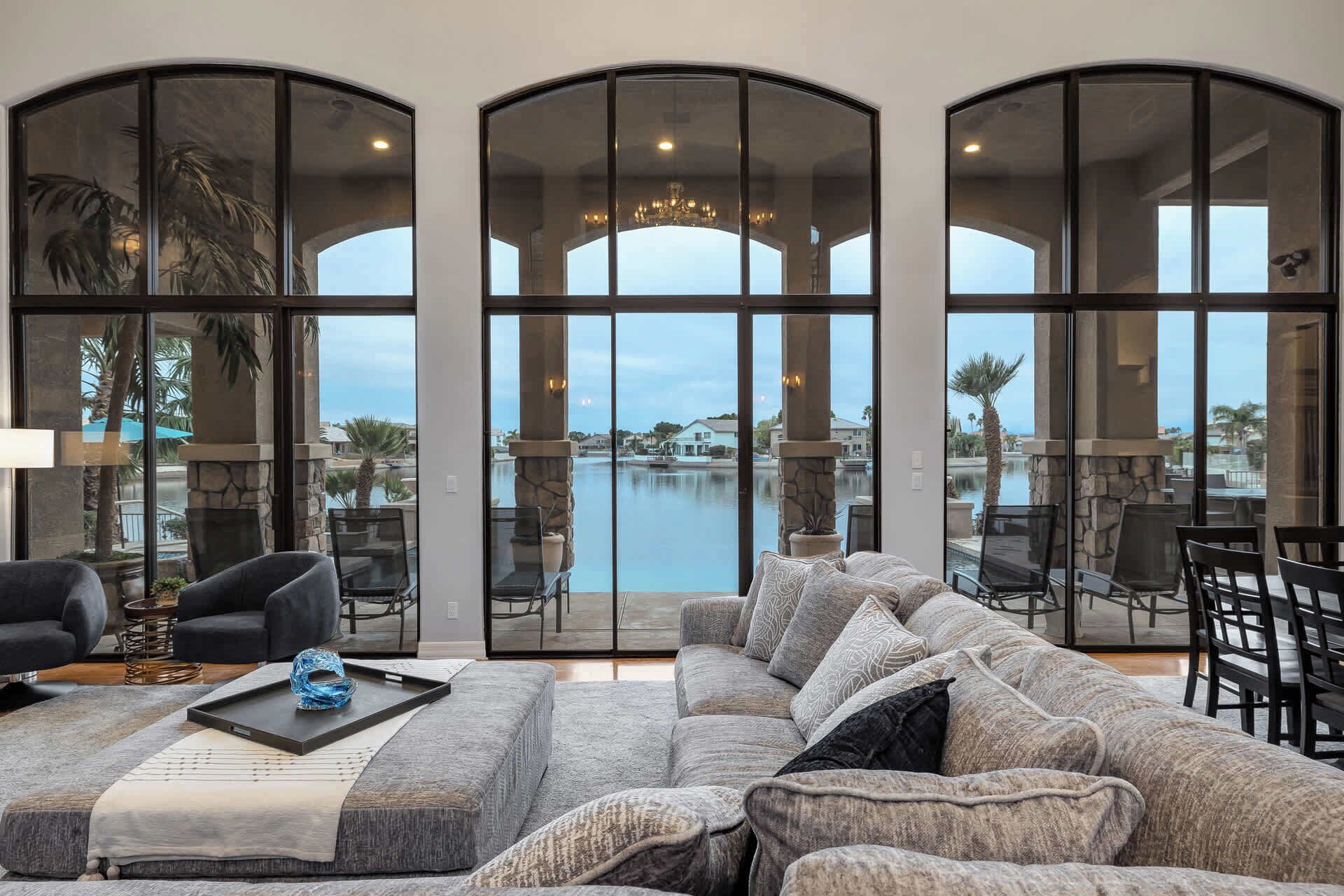 A spacious living room with a large sectional sofa, a fireplace, and a view of a swimming pool and houses.