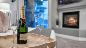 A bottle of Moët & Chandon champagne on a tray with two glasses, a fireplace, and a blurred background. - The Estate | Lake Views w/Heated Pool, Spa, & Boat (Glendale)