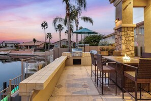 An outdoor patio with a grill, wicker furniture, and a view of a marina. - The Estate | Lake Views w/Heated Pool, Spa, & Dock (Glendale)