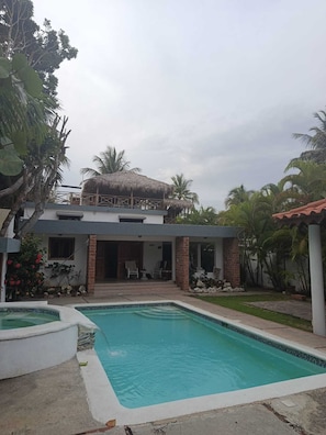 A residential property with a swimming pool, a covered patio, and a thatched-roof structure. - Air-conditioned house on a Caribbean beach with a pool and hot tub (Playa Juan Dolio)