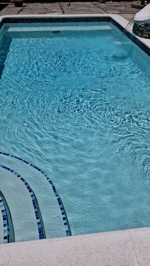 Una piscina rectangular amb aigua blava cristal·lina i un videt de rajoles.