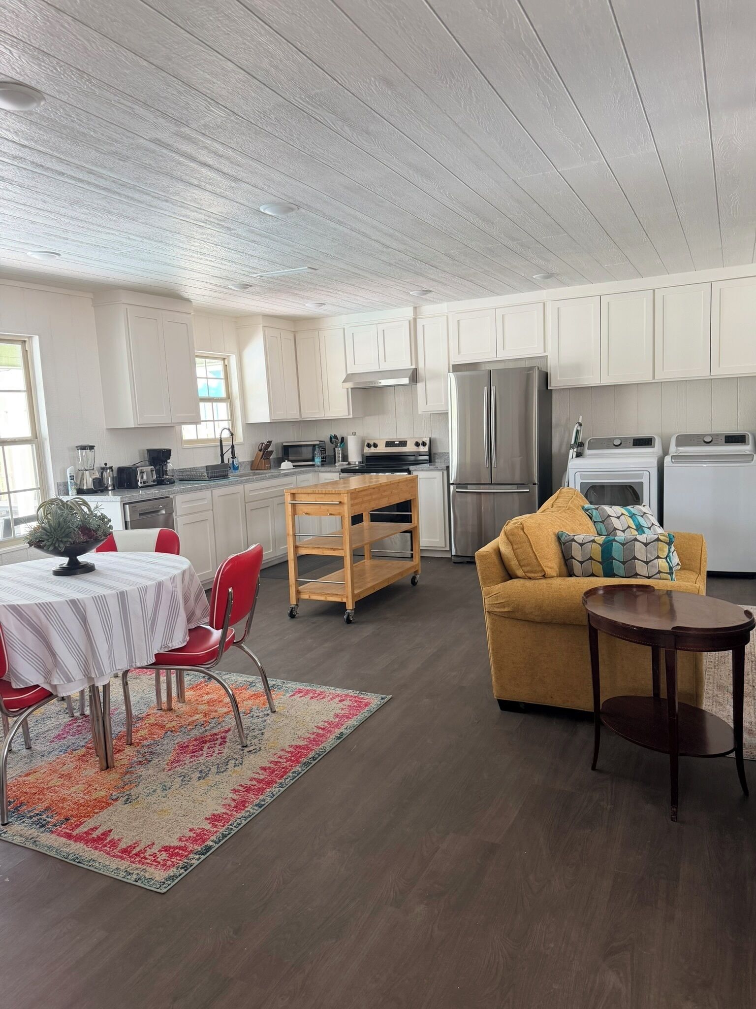 A modern kitchen with white cabinets, stainless steel appliances, and a dining area with a table and chairs.