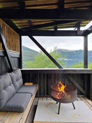 Una terraza de madera con un sofá y un hogar a fuego metálico.