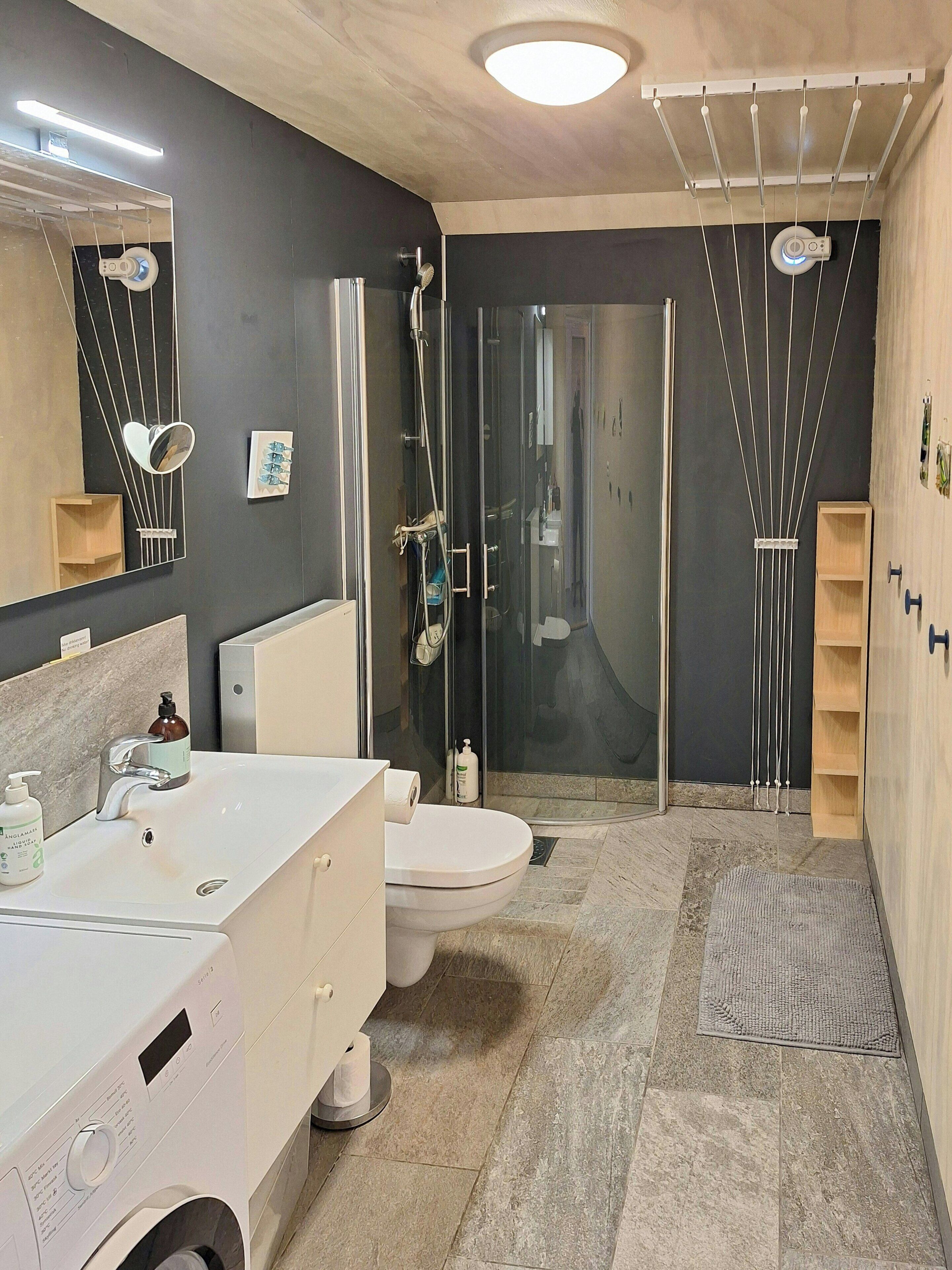 A modern bathroom with a glass-enclosed shower, a white sink, and a mirror.