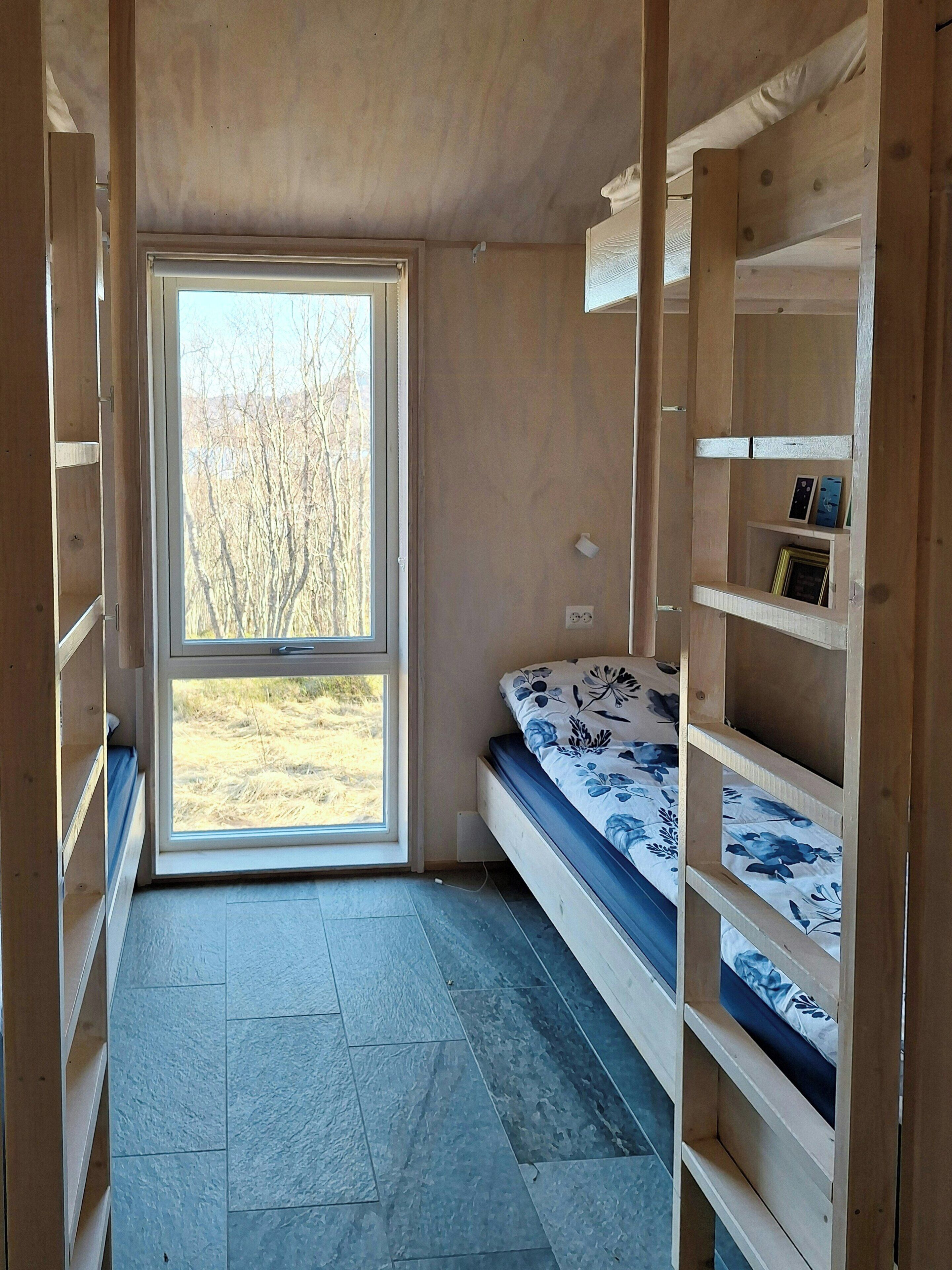Ein Zimmer mit einem Bett, integrierten Regalen und einem großen Fenster.