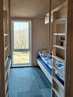 Una habitación con cama, estanterías integradas y un ventanal amplio.