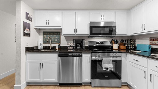 A modern kitchen with white cabinets, stainless steel appliances, and a coffee machine. - Roark Creek View - Pool & Gym (Branson)