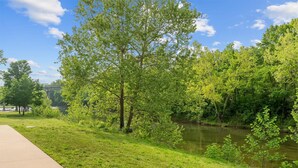 A park with a river, trees, and a concrete path. - Roark Creek View - Pool & Gym (Branson)