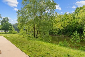 Ein Park mit Fluss, Bäumen und einem Betonweg.