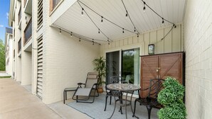 A covered patio with a table and chairs, a potted plant, and a wooden cabinet. - Roark Creek View - Pool & Gym (Branson)