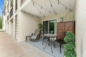 Eine überdachte Terrasse mit Tisch und Stühlen, einem Blumentopf und einem Holzschrank.