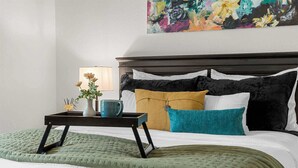 A neatly made bed with a green quilt, a bedside table with a vase of flowers, and a lamp. - Roark Creek View - Pool & Gym (Branson)