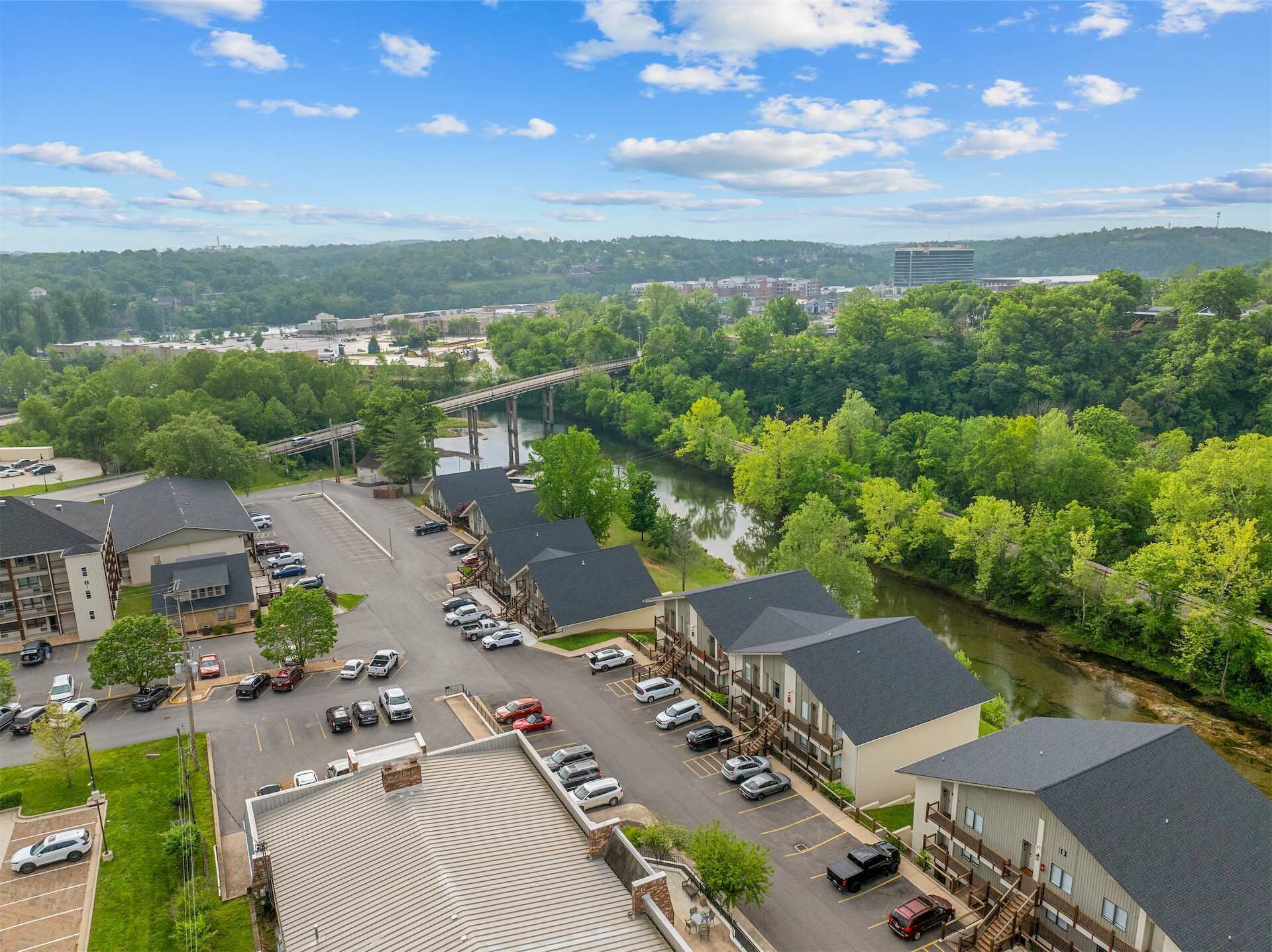 A multi-story hotel with a parking lot, a river, and a bridge in the background.