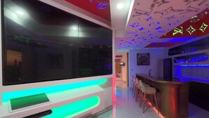 Un interior moderno con una zona de bar, un ventanal grande y un techo con diseños iluminados.
