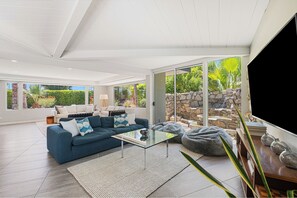 Ein modernes Wohnzimmer mit einem blauen Sofa, einem Glastisch und einer Steinwand.
