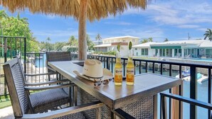 Un balcon avec des meubles en osier, une table et deux bouteilles de bière Corona.
