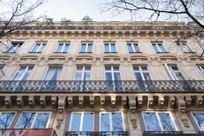 Ein mehrstöckiges Gebäude im klassischen Stil mit einem Balkon und aufwendigen Brüstungen.