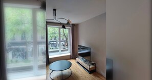 Ein Zimmer mit einem großen Fenster, einem runden Tisch und einer integrierten TV-Konsole.