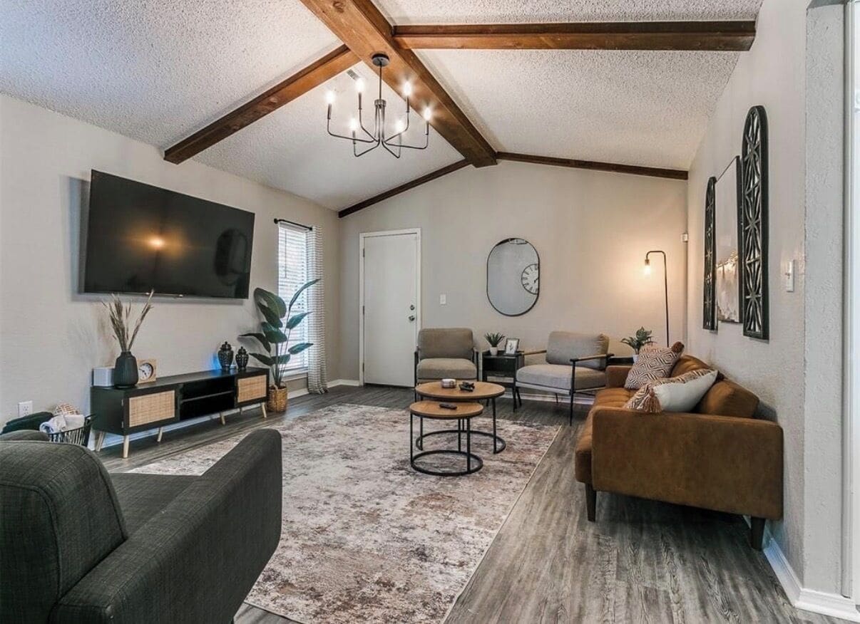 A living room with a flat-screen TV, two sofas, a coffee table, and a chandelier.