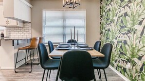 A dining area with a table set for four, black chairs, a wooden table, and a geometric chandelier. - Newly Remodeled 3 BR House w/ Fire Pit, 5 min. From Stadium! (Norman)