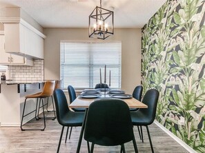 A dining area with a table set for four, black chairs, a wooden table, and a geometric chandelier. - Newly Remodeled 3 BR House w/ Fire Pit, 5 min. From Stadium! (Norman)