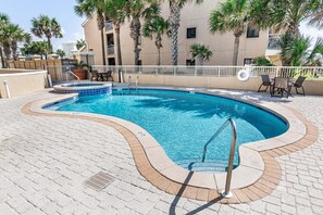 A swimming pool with a curved edge, a lifeguard chair, and a lounge area with chairs and a table. - Dunes of Crystal Beach 404 - Beachfront Condo with Community Pool in Destin (Destin)