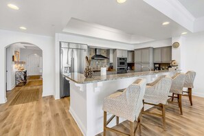 A modern kitchen with a central island, bar stools, and a built-in oven. - Dunes of Crystal Beach 404 - Beachfront Condo with Community Pool in Destin (Destin)